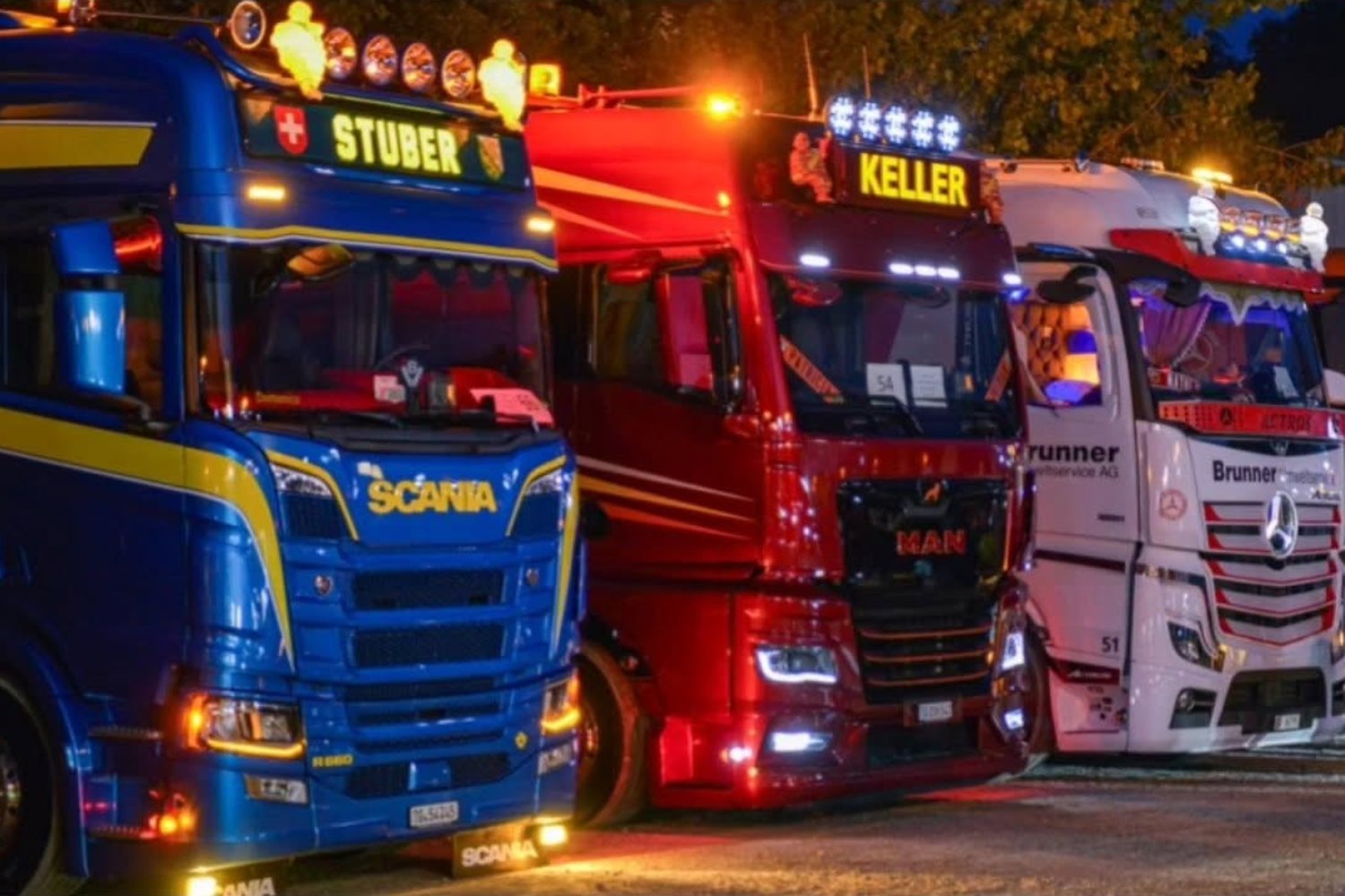 Beleuchtete Lastwagen in einer Reihe am Abend der Trucker-Chilbi